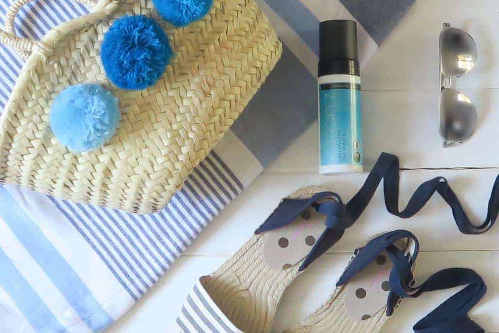 A summer flatlay; hammam towel, espadrilles, pom pom wicker basket, sunglasses and St Tropez Gradual One minute tan to illustrate my St Tropez Gradual One Minute Tan Review 