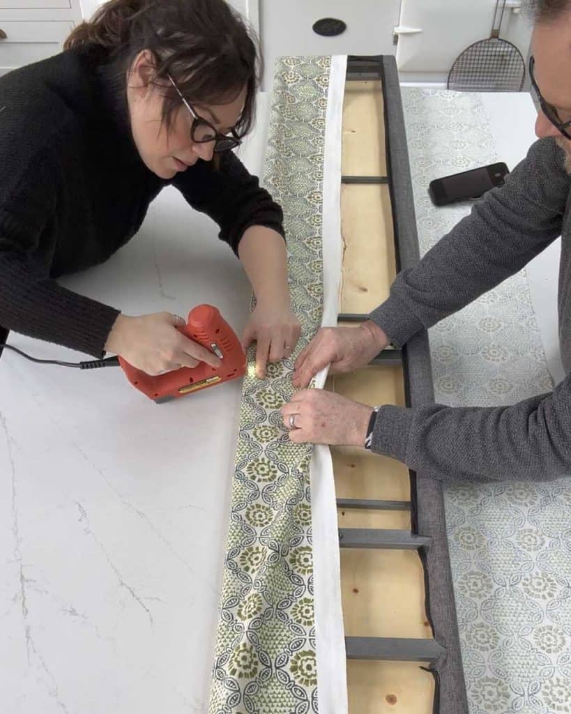 6. How to Upholster a Headboard and Bedframe: Fold over one side of the fabric, then using your staple gun, staple the fabric down onto the back of the headboard. 