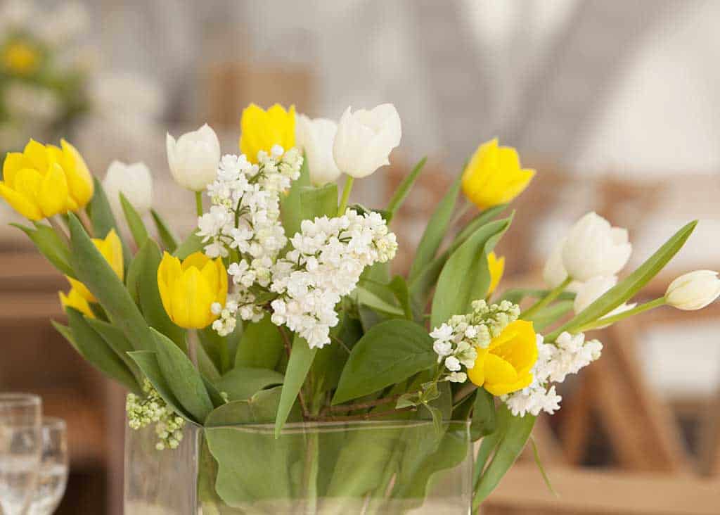 Decorations for Baby Naming Ceremony — yellow and white flowers in simple glass vases.