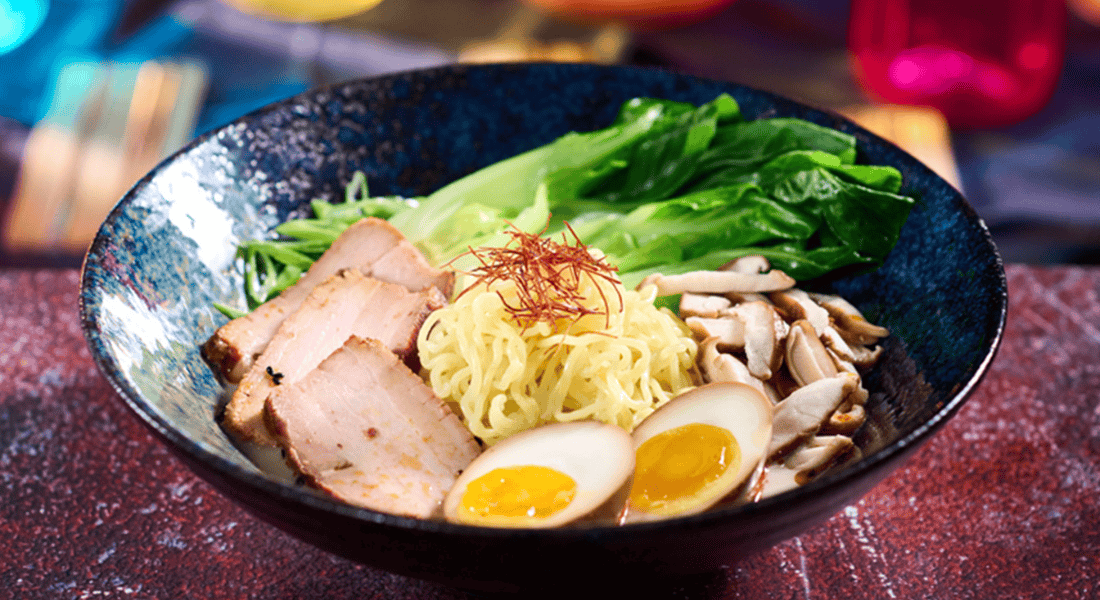 Tonkotsu Ramen at The Blue Dragon Pan-Asian Restaurant. This Asian comfort food features delicate ramen noodles immersed in a rich pork broth, topped with tender chashu pork, tare egg, shiitake mushrooms, and fragrant togarashi oil. Photo courtesy of ©Universal Orlando Resort.