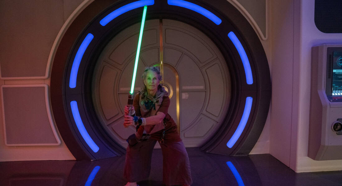 Halcyon Daze Director Carrie Coaplen dons a lightsaber on board the Halcyon during the Star Wars: Galactic Starcruiser experiences (Photo courtesy of Halcyon Daze)
