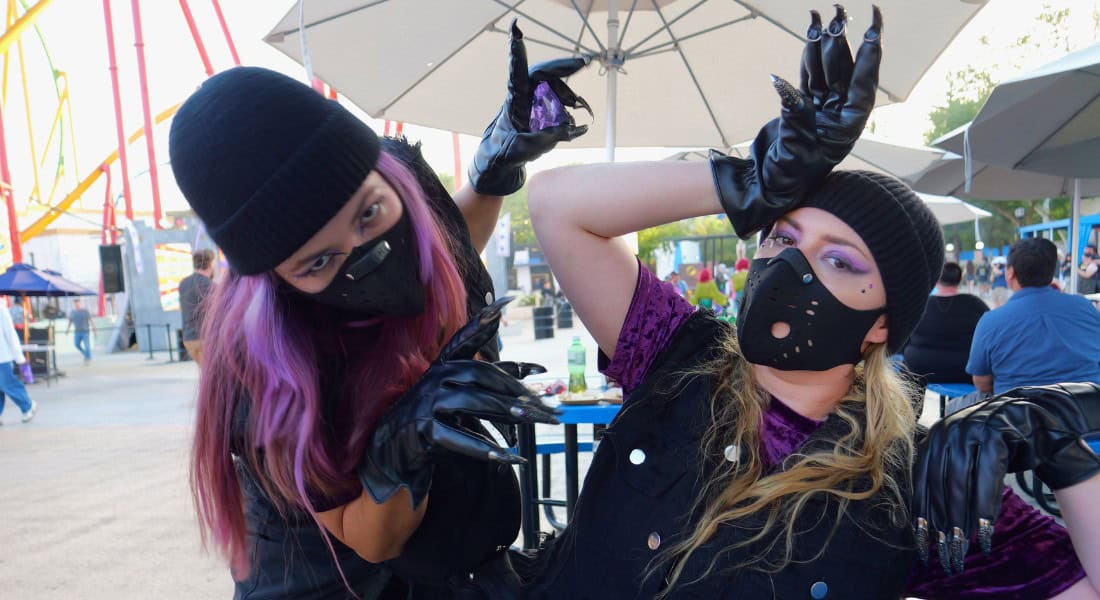 Two of Catwoman's sidekicks try to convince a guest to give up his camera in exchange for a purple jewel that one holds in her hand. (photo by Joe Tracy for Theme Park Magazine)