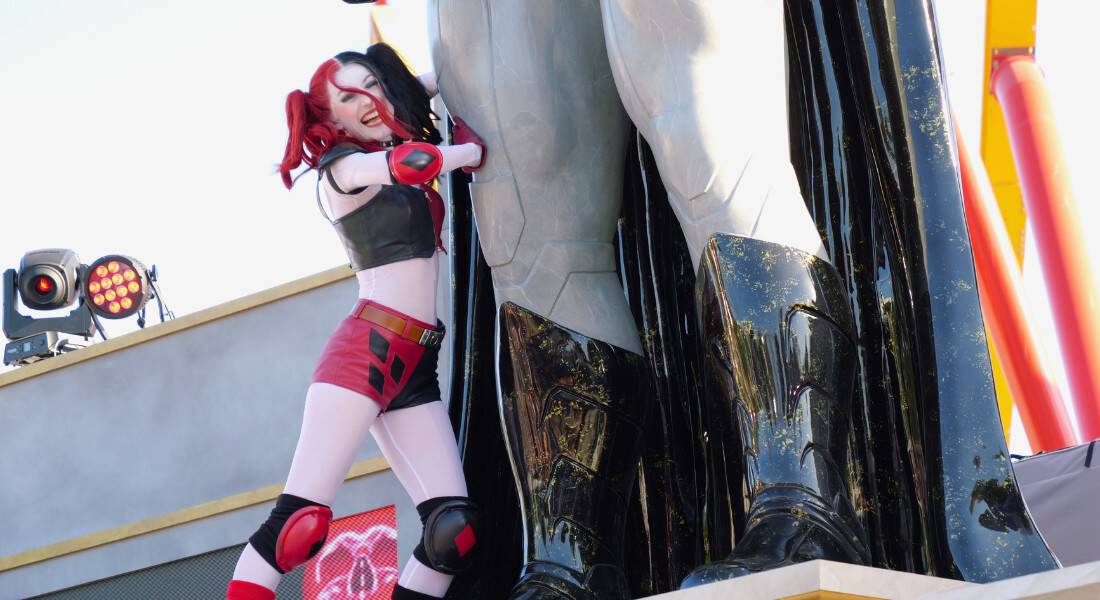 Harley Quinn pushes against the giant Batman statue in an attempt to topple it. (photo by Joe Tracy for Theme Park Magazine)