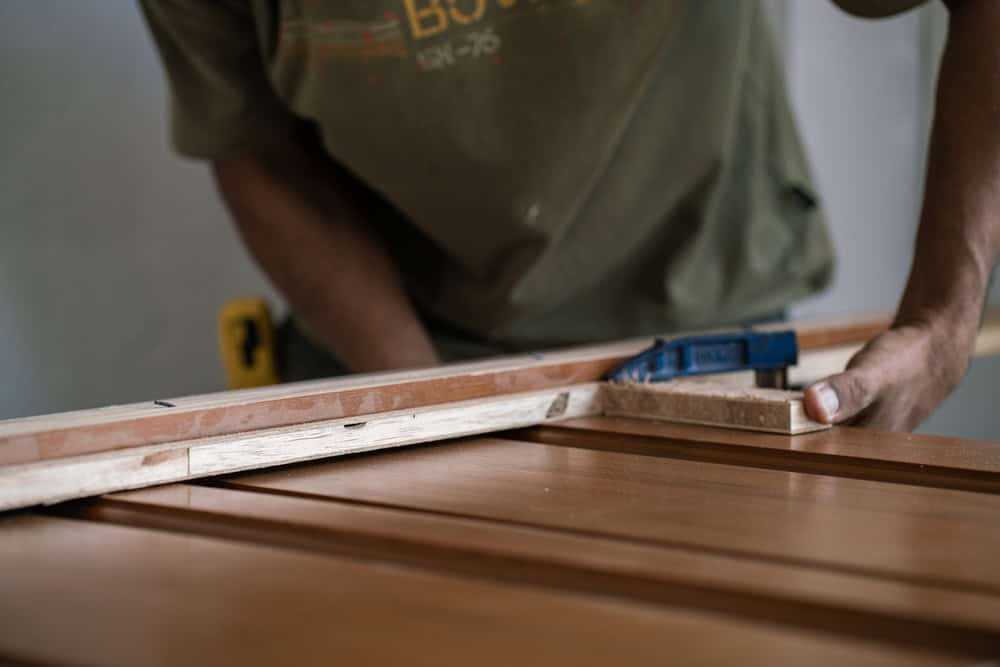 Carpenter,Man,Working,With,Teak,Wooden,Door,Installation,In,New