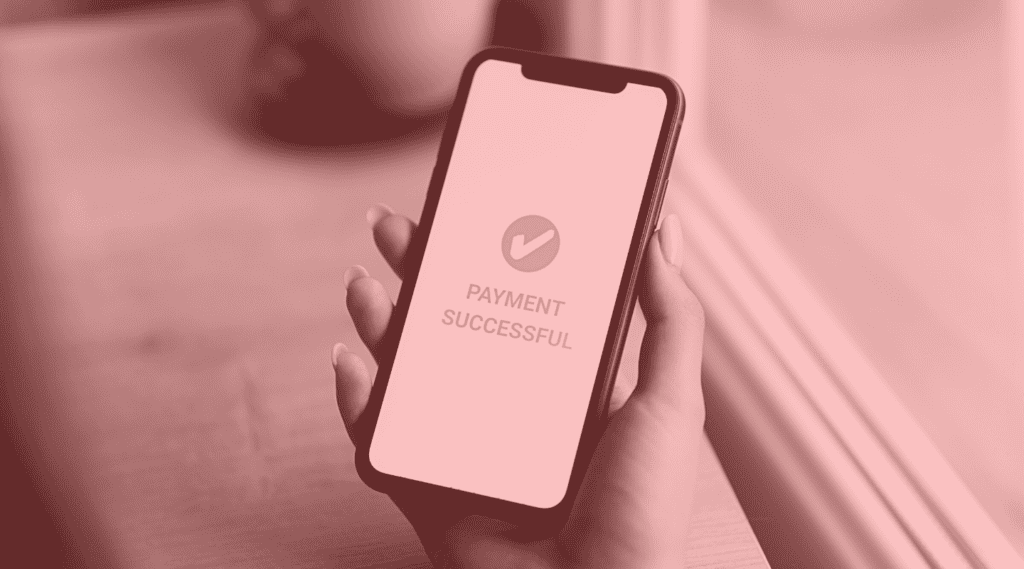 Hand holding a cell phone that shows a checkmark and words Payment Successful to signify concept of payment orchestration