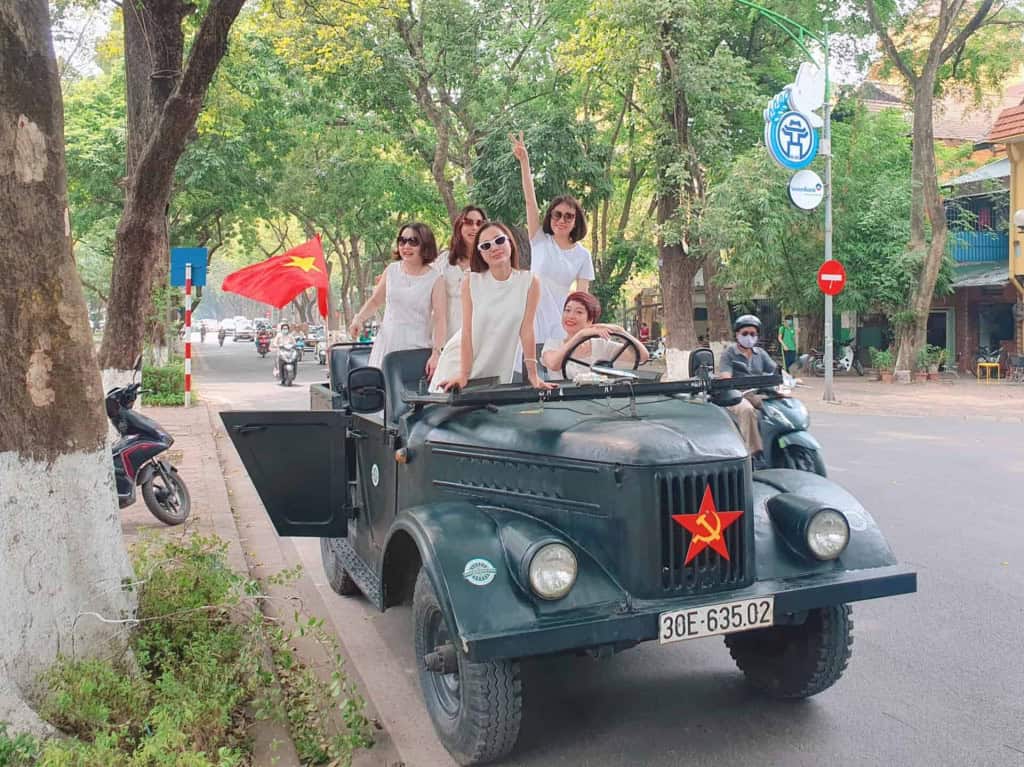 Jeep tour with group of tourists in Hanoi, Vietnam, exploring the city streets.