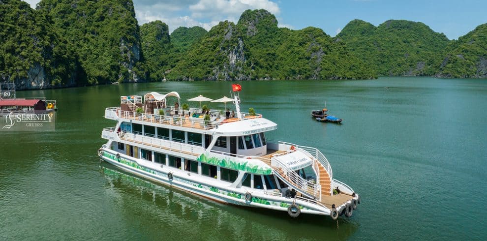 Serenity Cruise boat floating on tranquil Lan Ha Bay surrounded by lush green karst formations.
