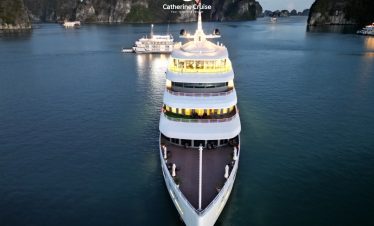 Luxurious cruise ship sailing in emerald waters among limestone karsts in Ha Long Bay.