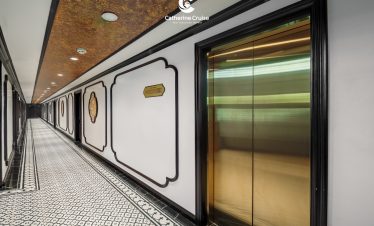 Modern hotel corridor with elegant black and white decor and gold elevator doors.