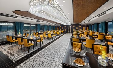 Elegant restaurant interior with yellow chairs, crystal chandelier, and decorative tiles, ideal for fine dining and events.