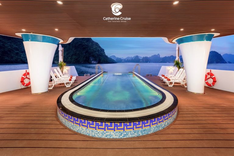 Luxury cruise ship pool with scenic limestone islands in the background.