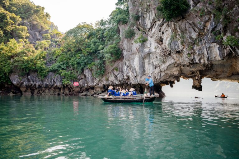 Skim beneath a natural stone archโgentle rowing, crisp air, and sparkling reflections.
