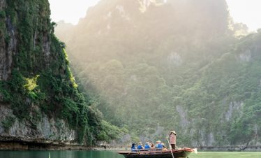 Tranquil boat tour through lush green limestone karsts in Halong Bay, Vietnam.