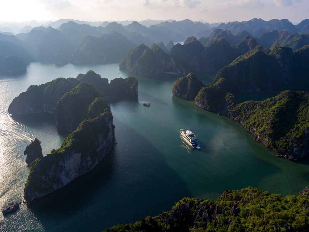 Drone view of Stellar Of The Seas weaving through dramatic karst islands in Lan Ha Bay, Vietnam. Let ViettrendTour craft your dream Halong Bay cruise itinerary.
