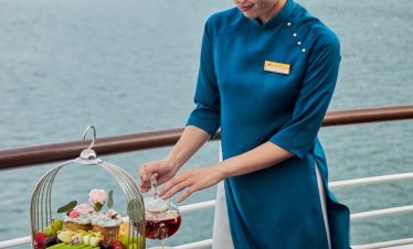 Elegant cruise staff preparing afternoon tea on a luxury voyage in scenic nature setting.