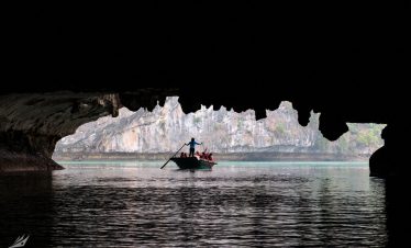 A boat cruising through a scenic water cave with stunning rock formations and lush cliffs.