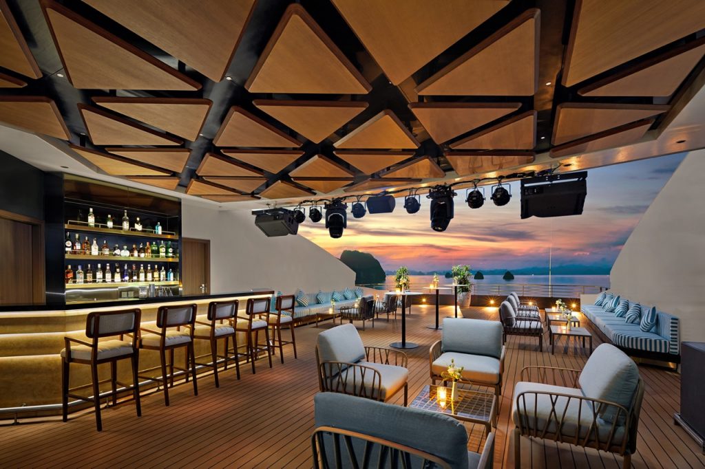 Relaxing rooftop bar with ocean view at sunset, ideal for luxury travel and tropical vacations.