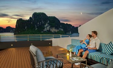 Relaxing couple on a sunset cruise in Ha Long Bay, Vietnam, with stunning limestone karsts and ocean views.