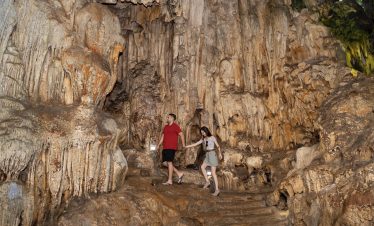 Stunning cave exploration with couple amid stalactites and stalagmites in Vietnam.