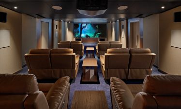 Comfortable private home theater room with leather recliners and large screen for movies.