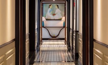 Elegant cruise hallway with intricate tile flooring and artistic wall decor.