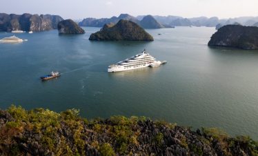 Luxury cruise ship in Halong Bay, Vietnam with emerald waters and limestone karsts.
