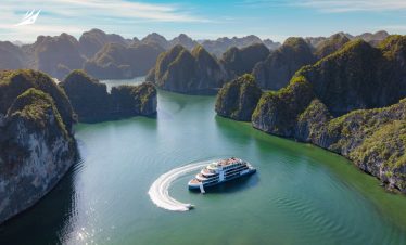 Spectacular boat cruising through emerald waters amidst towering limestone islands in Ha Long Bay, Vietnam.