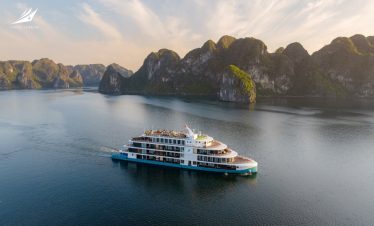 Luxury cruise boat sailing through stunning limestone karsts on Halong Bay, Vietnam.