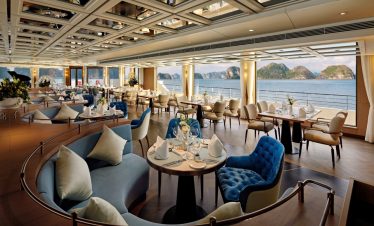 Luxurious cruise ship restaurant with panoramic ocean views and elegant decor.