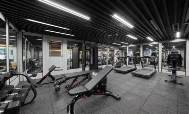 Modern gym with cardio and strength equipment in a sleek, well-lit fitness center.