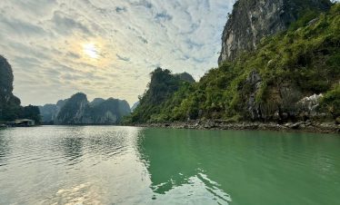 Tranquil river surrounded by lush green limestone mountains in Vietnam.