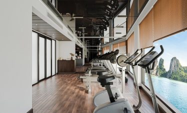 Modern gym room with exercise bikes and panoramic water views for fitness and relaxation.