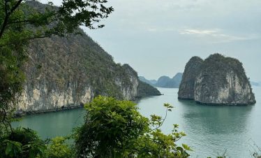 Limestone karsts and emerald waters of Ha Long Bay, Vietnam, surrounded by lush greenery.
