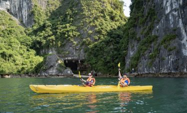 ViettrendTour - Scenic kayaking adventure in emerald green waters and lush limestone cliffs.