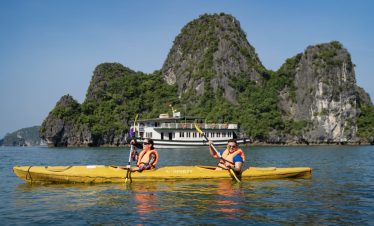 Kayakers enjoying the scenic Halong Bay tour in Vietnam with limestone karsts and boat cruises.
