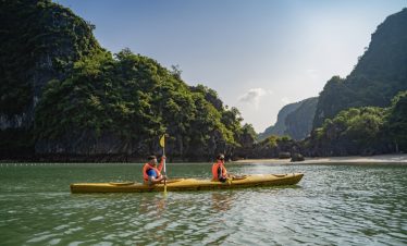 Tranquil kayak ride through lush green limestone islands and clear waters in Vietnam.