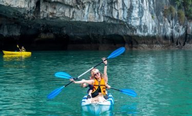 Kayaking in clear turquoise water near rocky cliffs, outdoor adventure activity in Vietnam.