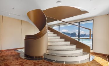 Luxurious spiral staircase with sea view in modern hotel interior.