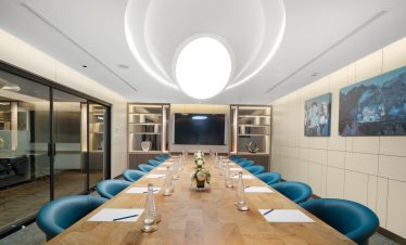 Elegant modern conference room with wooden table and blue chairs for business meetings.