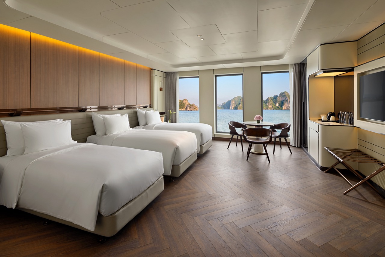 Luxury hotel room with sea view, three beds, modern decor, perfect for relaxing vacation.