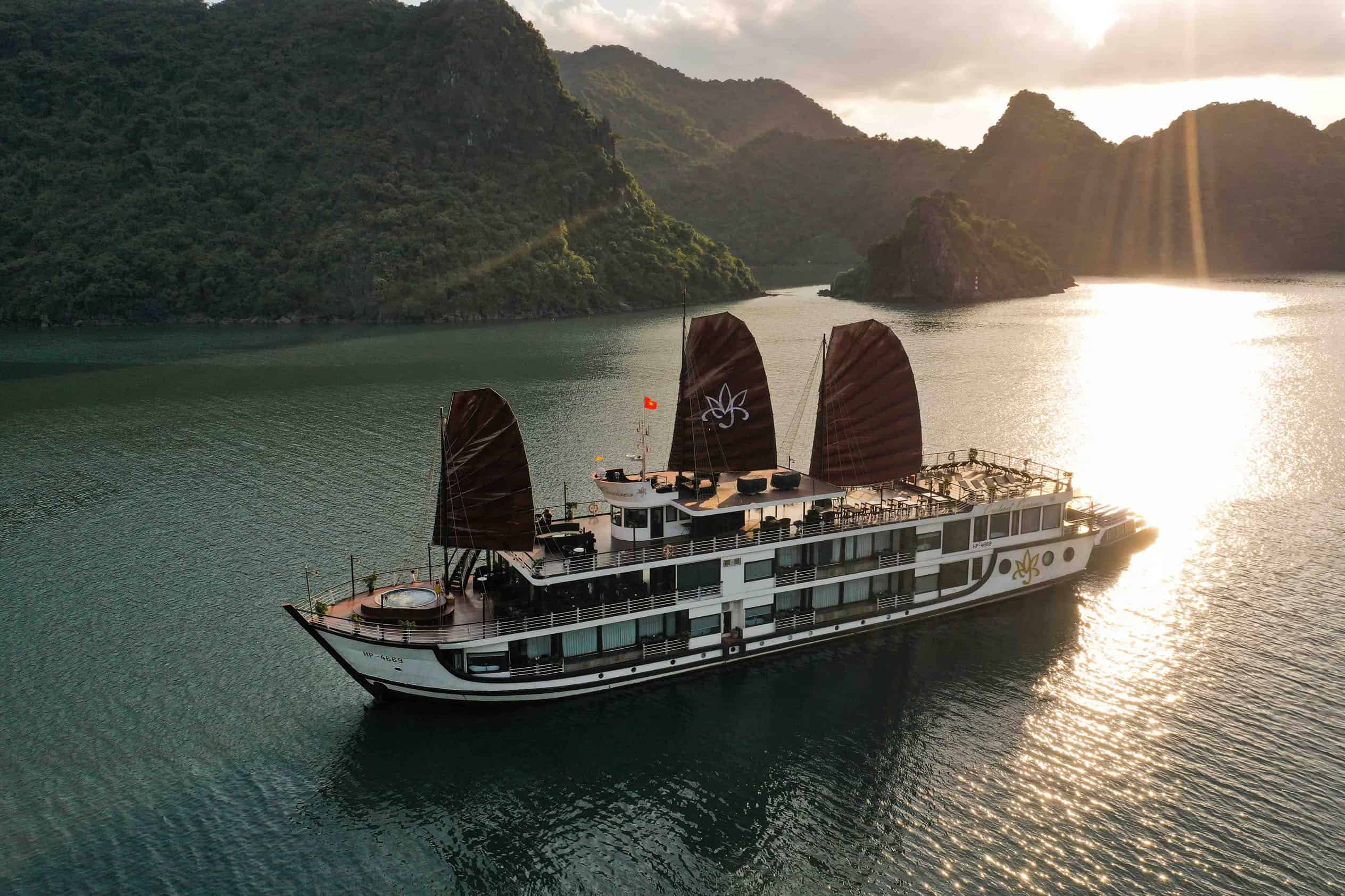Elegant cruise ship sailing through Halong Bay at sunset.