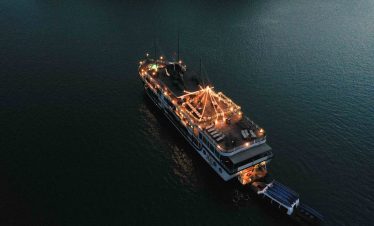 Elegant night cruise ship decorated with lights on calm water in Vietnam.