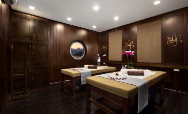Relaxing spa massage room with wooden walls, soft lighting, and floral decor at ViettrendTour spa.