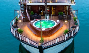 Luxury cruise ship with hot tub and outdoor seating on deck.
