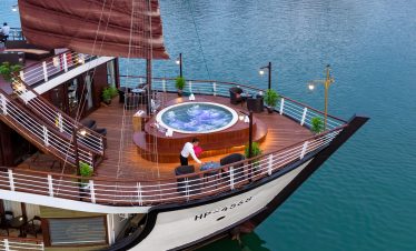 Luxurious cruise ship deck with hot tub and seaside dining, perfect for Vietnam island tours.