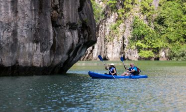 Kayakers exploring scenic limestone cliffs in Vietnam's tranquil waters.