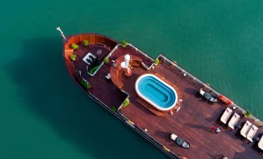 Aerial view of luxury cruise ship with pool, deck, and seating area on calm water, perfect for Vietnam travel.
