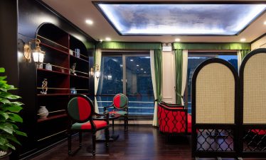 Elegant hotel lounge with classic furniture, wooden flooring, and scenic mountain views through large windows.