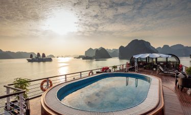 Luxury river cruise balcony with pool and scenic bay views at sunrise.
