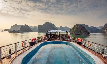 Luxury cruise ship with infinity pool and scenic karst islands in Halong Bay Vietnam.